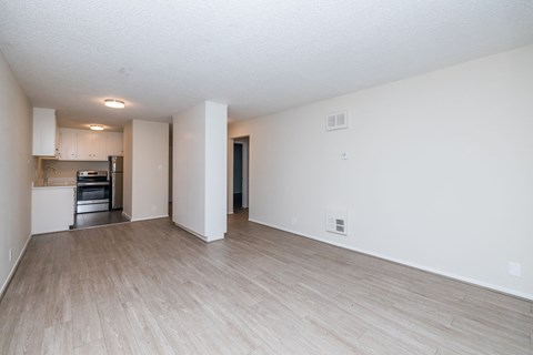 A spacious room with light wood flooring and white walls.