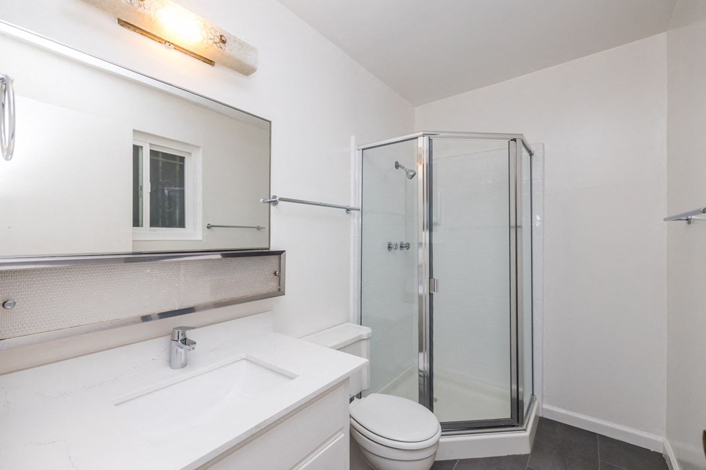 a white bathroom with a shower and a sink and a toilet