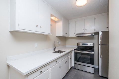 A kitchen with white cabinets and appliances.