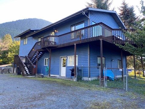 A blue house with a balcony and a staircase leading to the second floor.