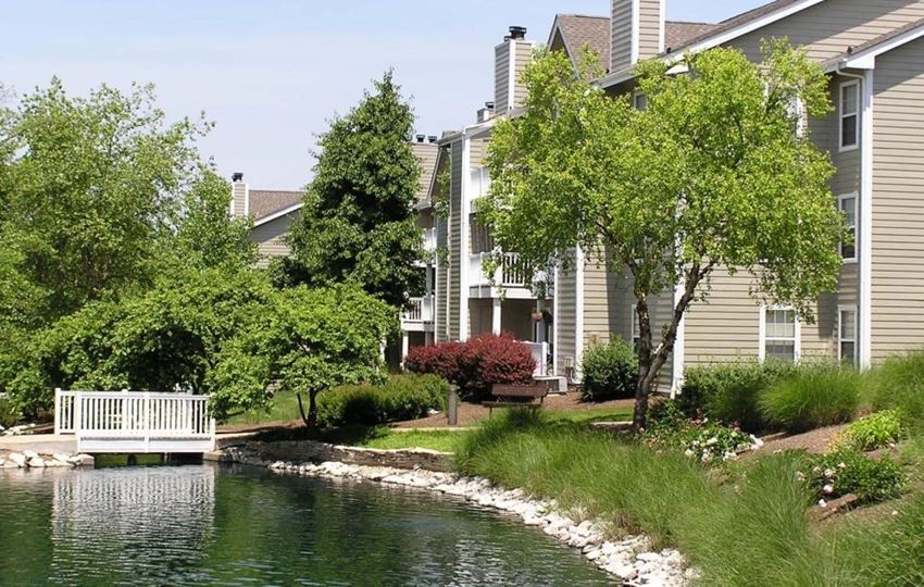 a white bench sitting next to a lake in front of a building