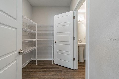 a walk in closet with an open white door