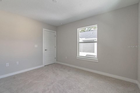 an empty bedroom with a window and a door