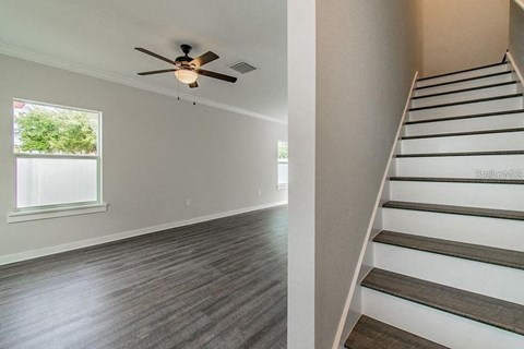 a living room with a staircase and a ceiling fan