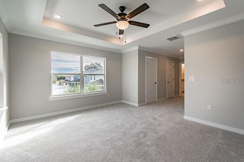 an empty living room with a ceiling fan and a window