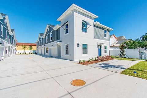 a white and blue house with a driveway in front of it