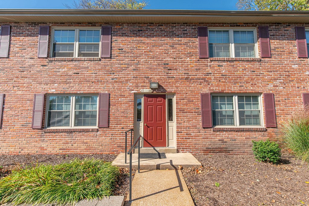 the front of a brick building with a red door