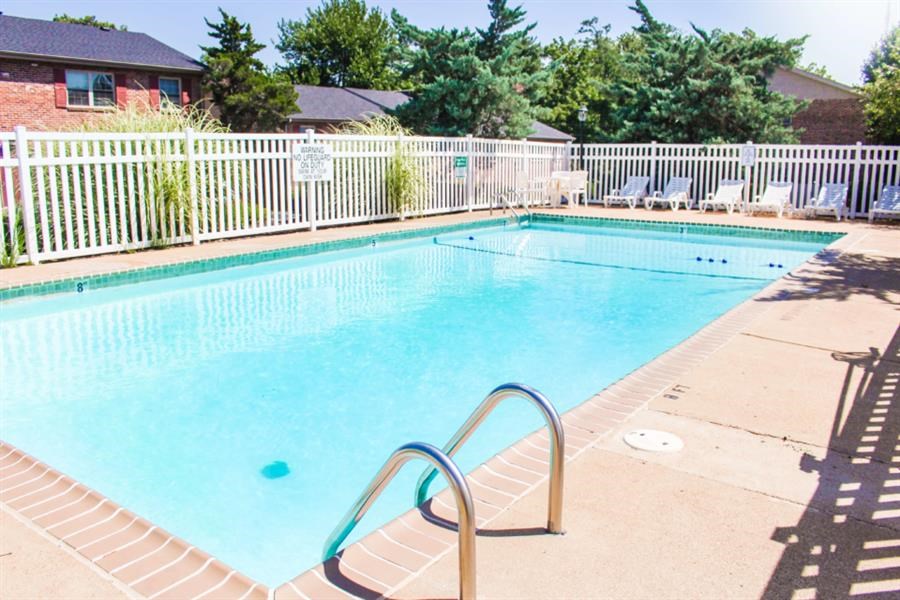 a swimming pool with a fence and chairs around it