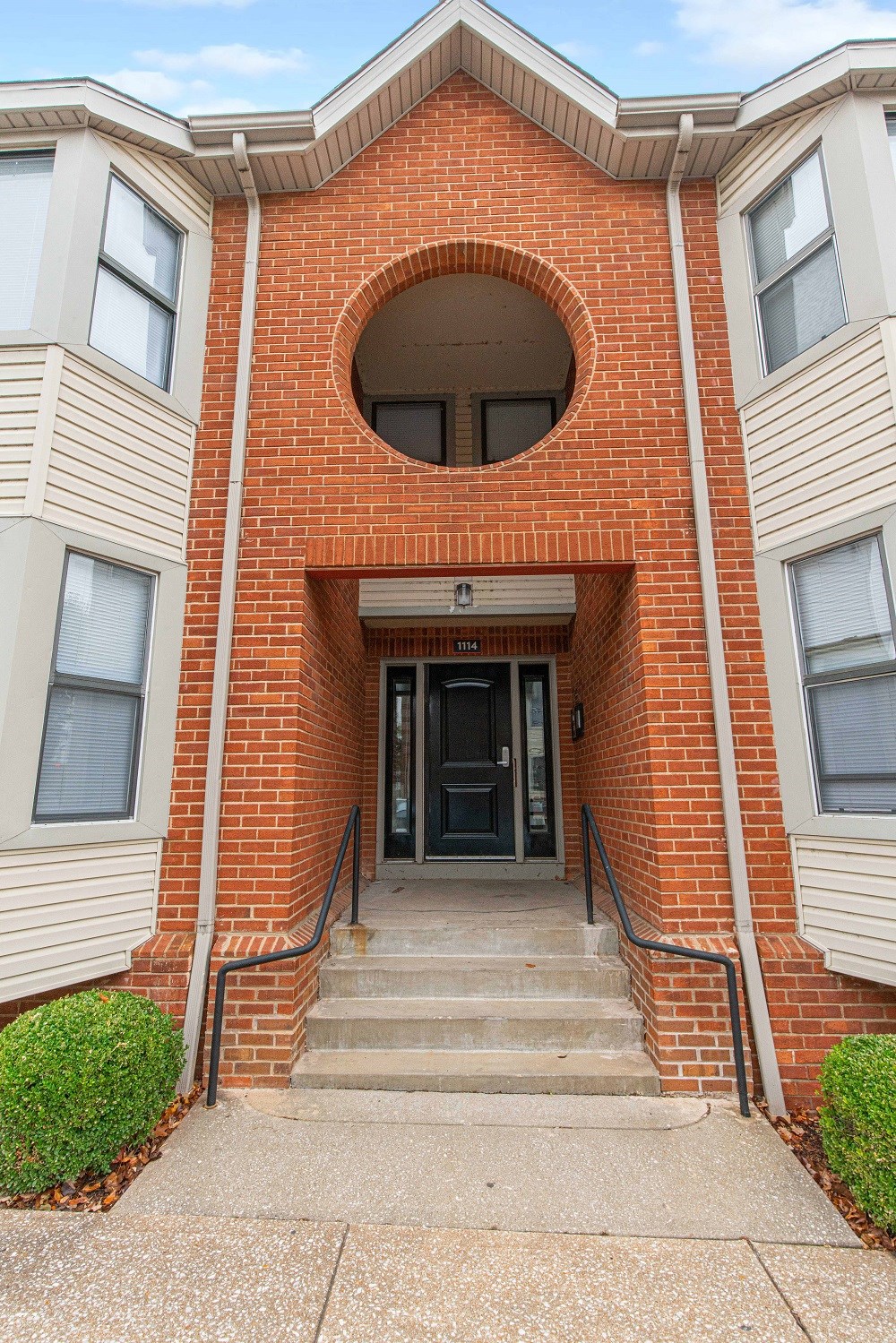 the front of a brick building with stairs and a black door