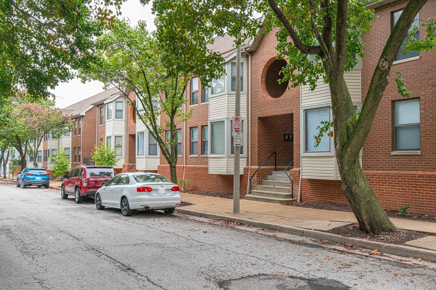 a city street with cars parked in front of a brick building