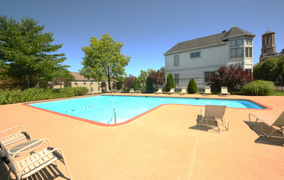a swimming pool with chairs and a house in the background