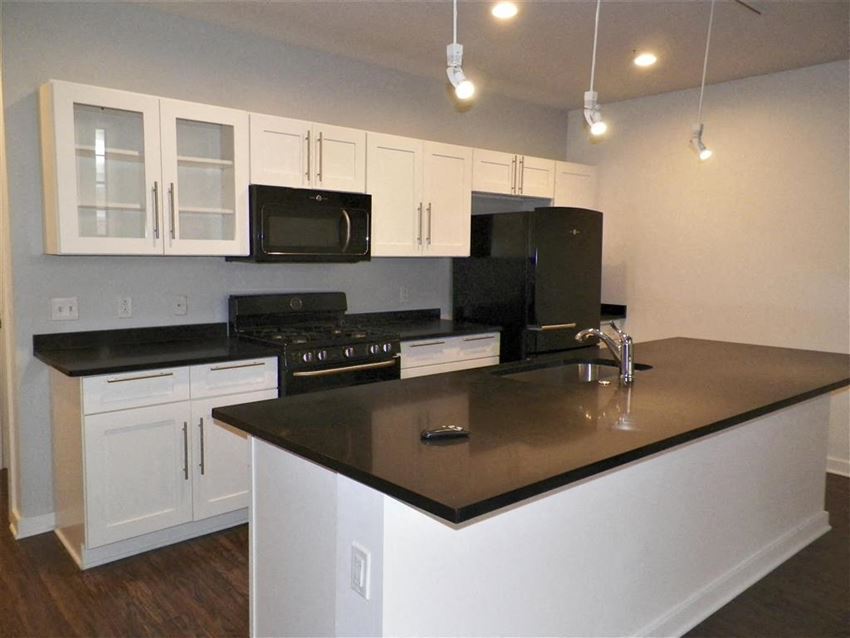 a kitchen with white cabinets and a black counter top