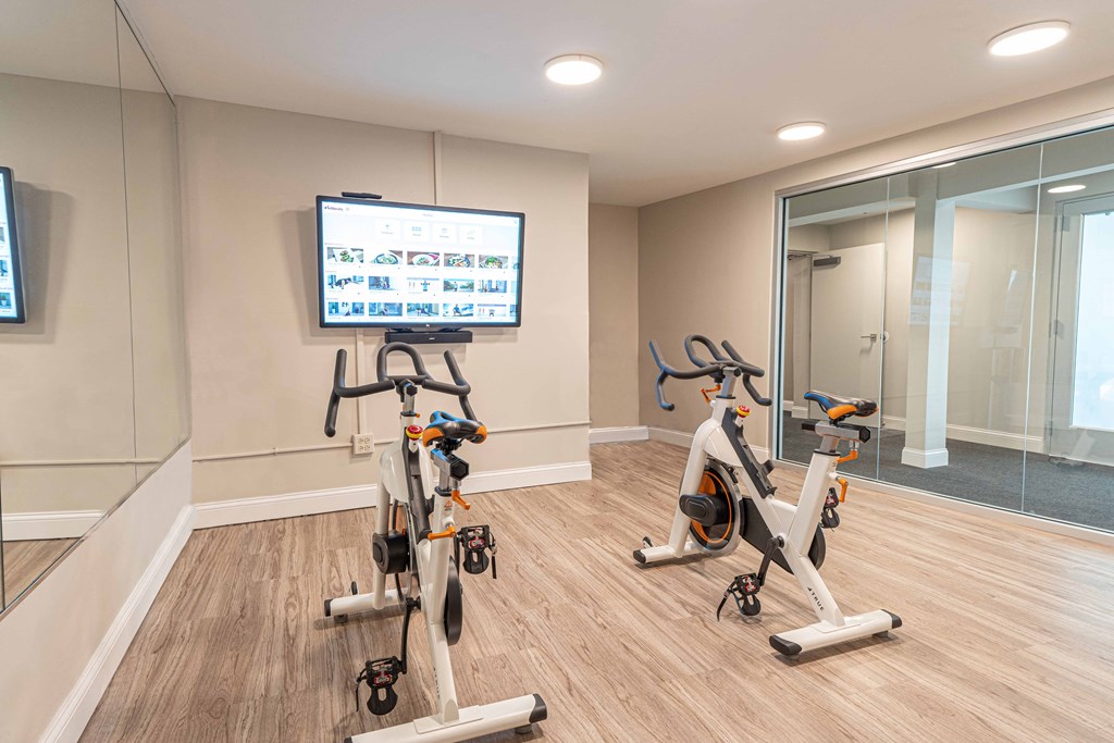 a gym with two exercise bikes and a tv on the wall