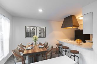 a dining area with a wooden table and chairs and a kitchen with a counter top