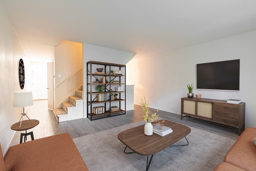 a living room with a couch and a tv and a staircase