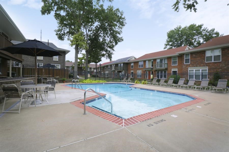 a swimming pool with tables and chairs in front of a building