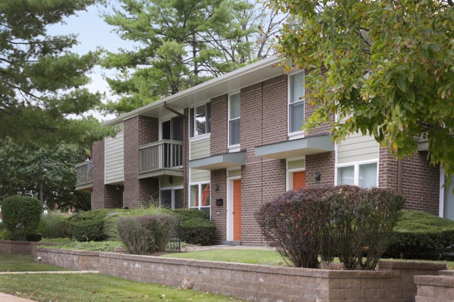 a brick apartment building with a lawn and trees
