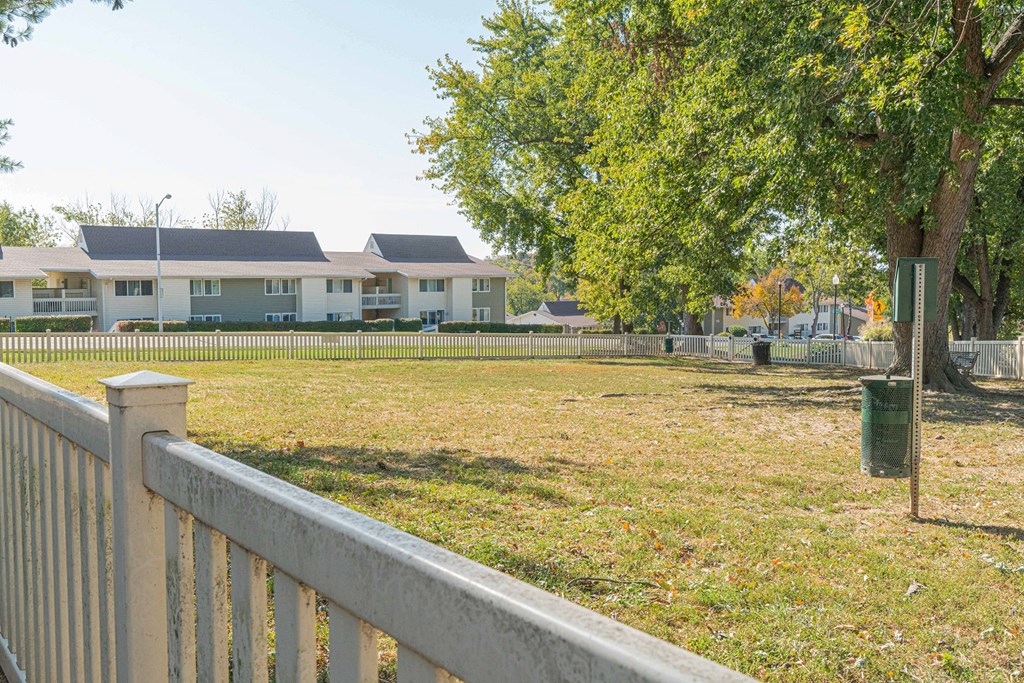 a yard with a fence and houses in the background