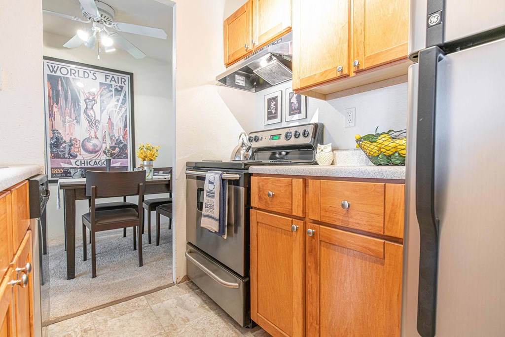 a kitchen with stainless steel appliances and wooden cabinets and a dining room with a table