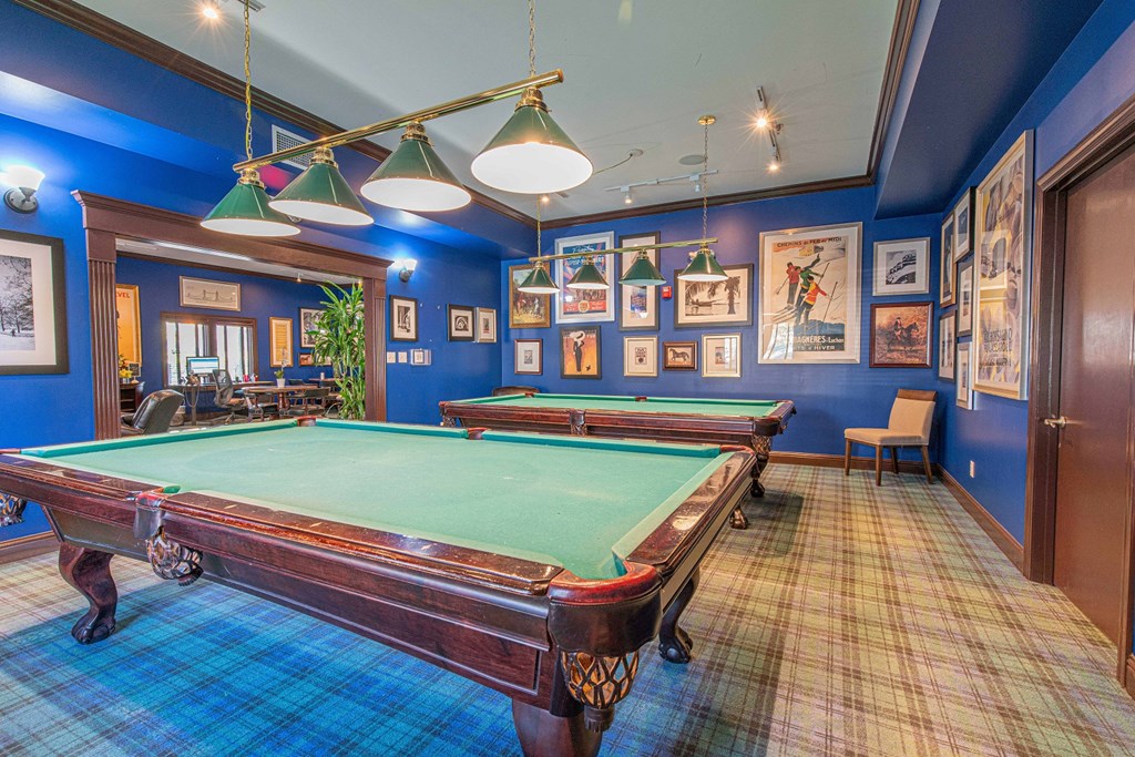 a game room with two pool tables and pictures on the wall