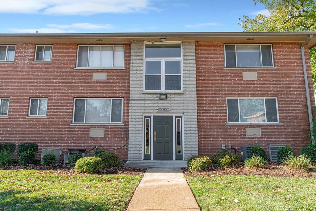 a brick apartment building with a sidewalk in front of it