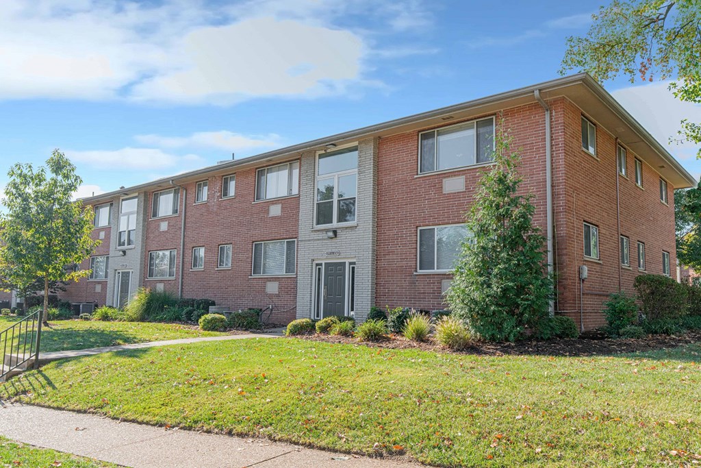 a brick apartment building with a sidewalk in front of it