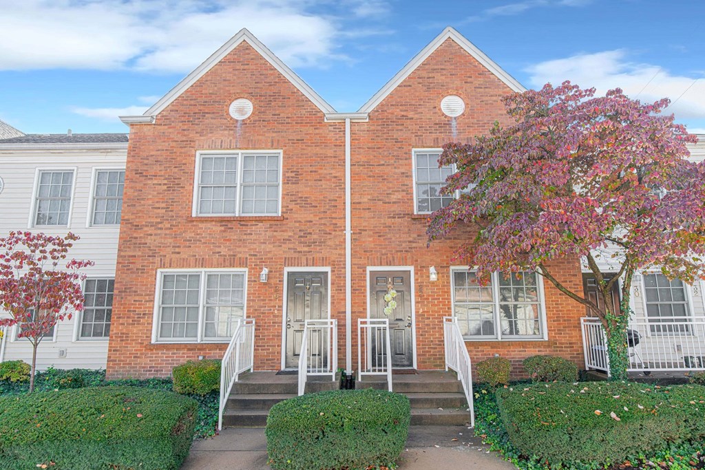 the front of a brick house with a tree in front of it