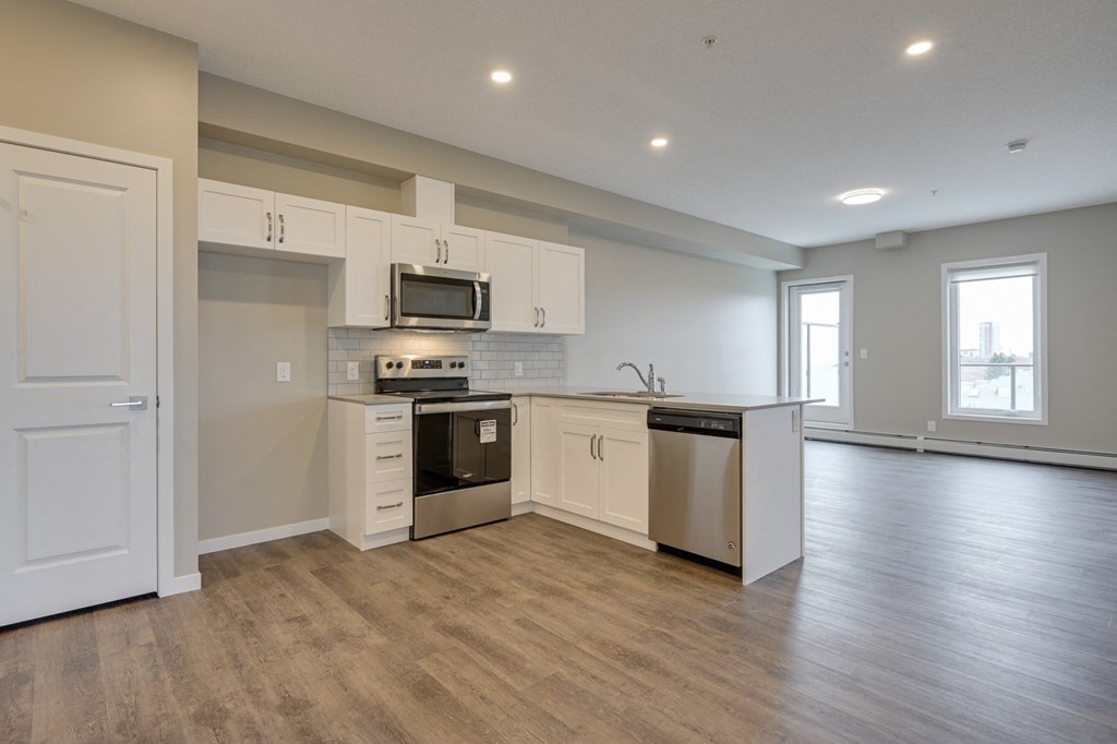 an empty kitchen with white cabinets and stainless steel appliances