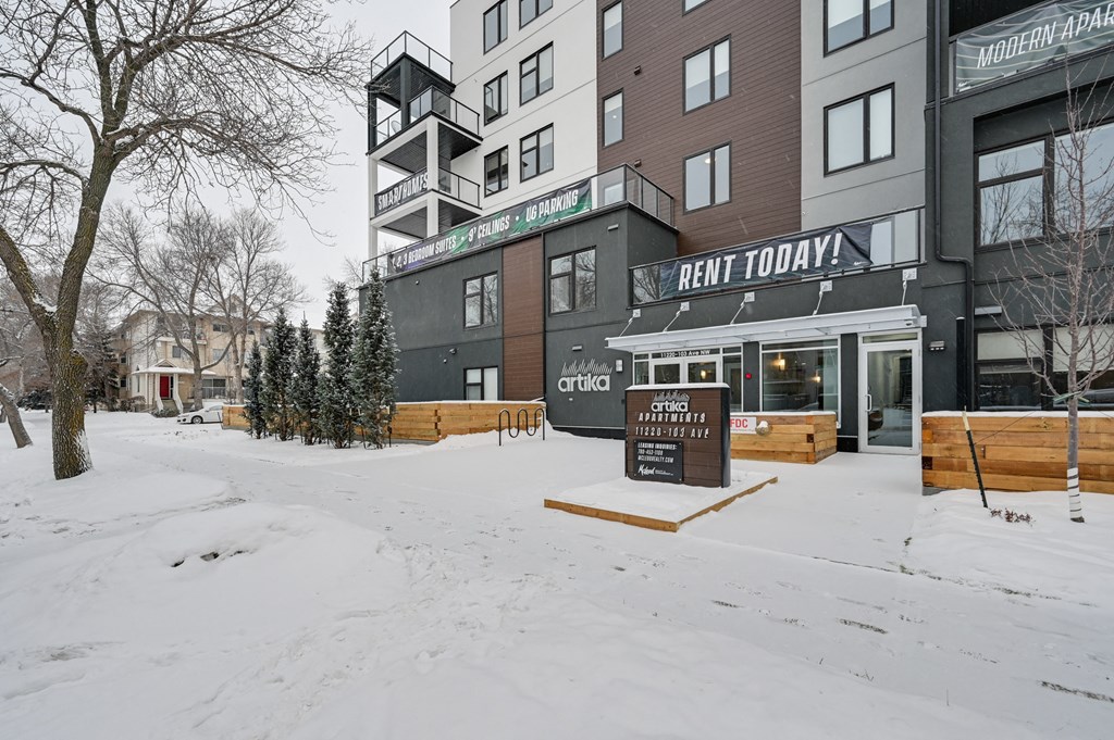 a snow covered sidewalk in front of a building with a sign