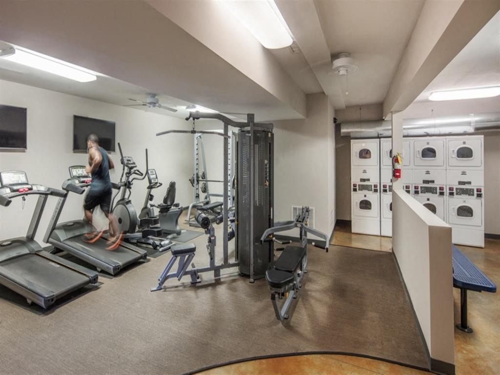 a woman walking on a treadmill in a gym with weights and other equipment