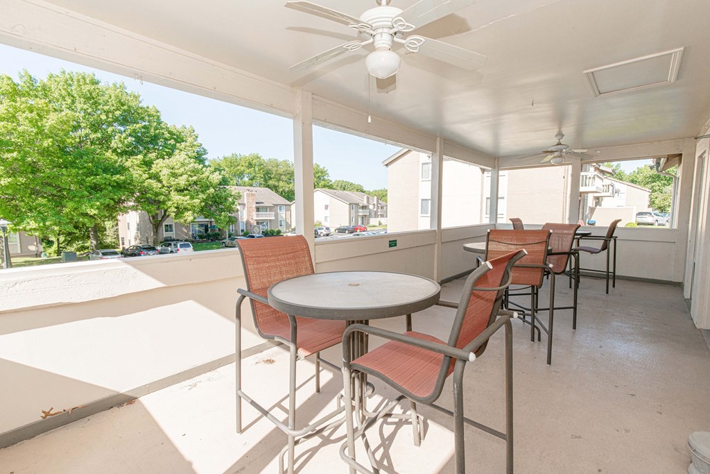 a patio with tables and chairs and a ceiling fan