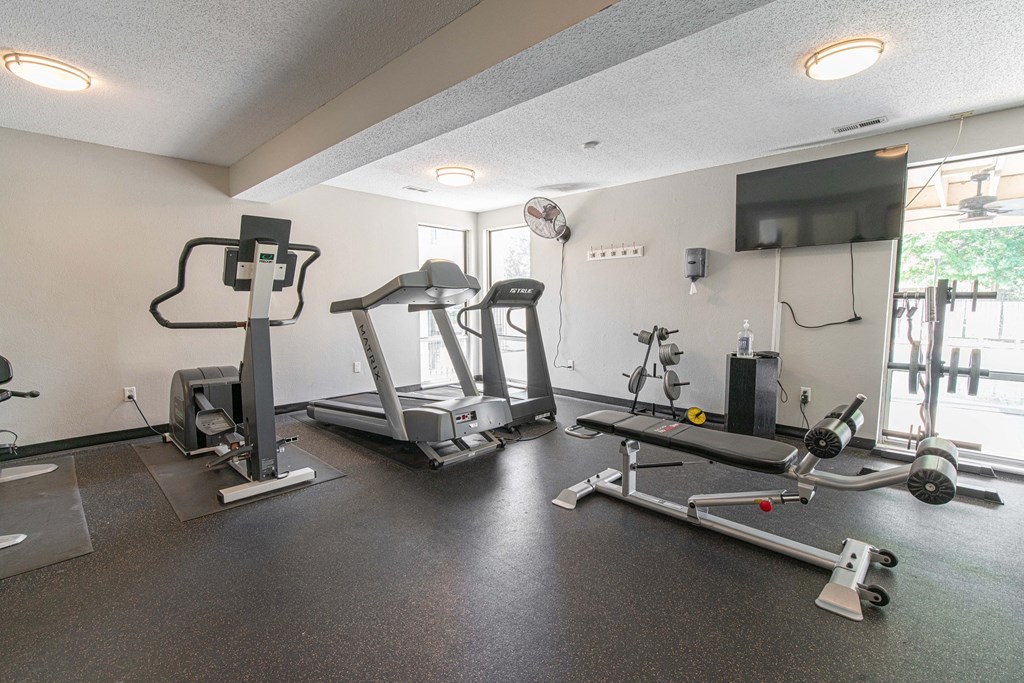 a gym with exercise machines and a tv on the wall