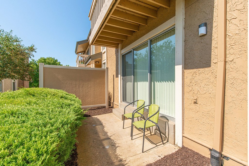 a patio with two chairs in front of a house