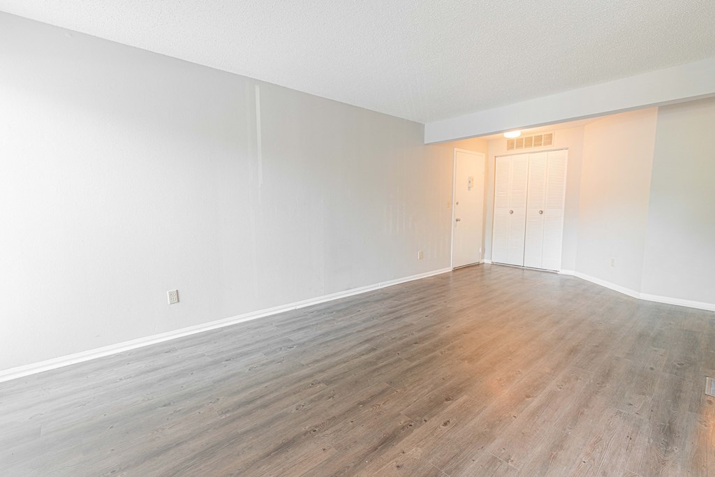 an empty living room with wood floors and white walls