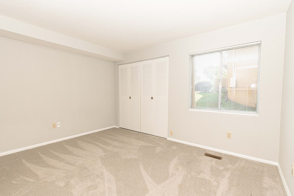 an empty living room with a window and a door to a closet