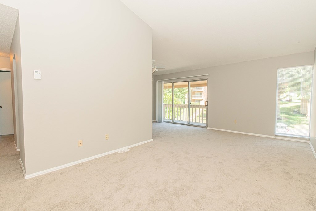 an empty living room with a sliding glass door to a patio