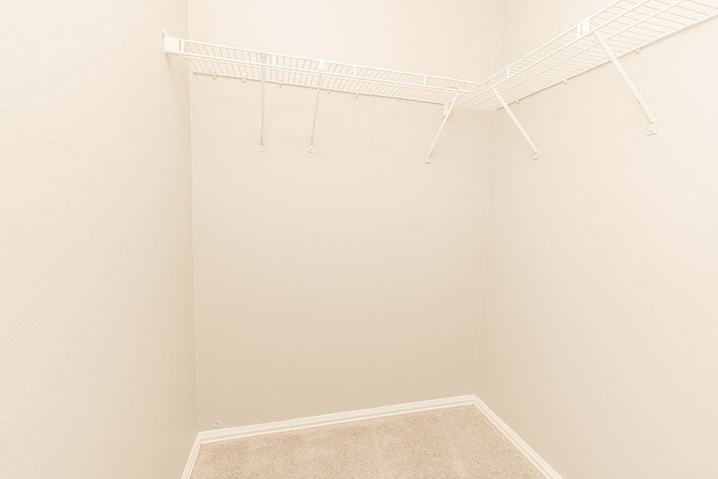 a spacious closet with white rods and a carpeted floor