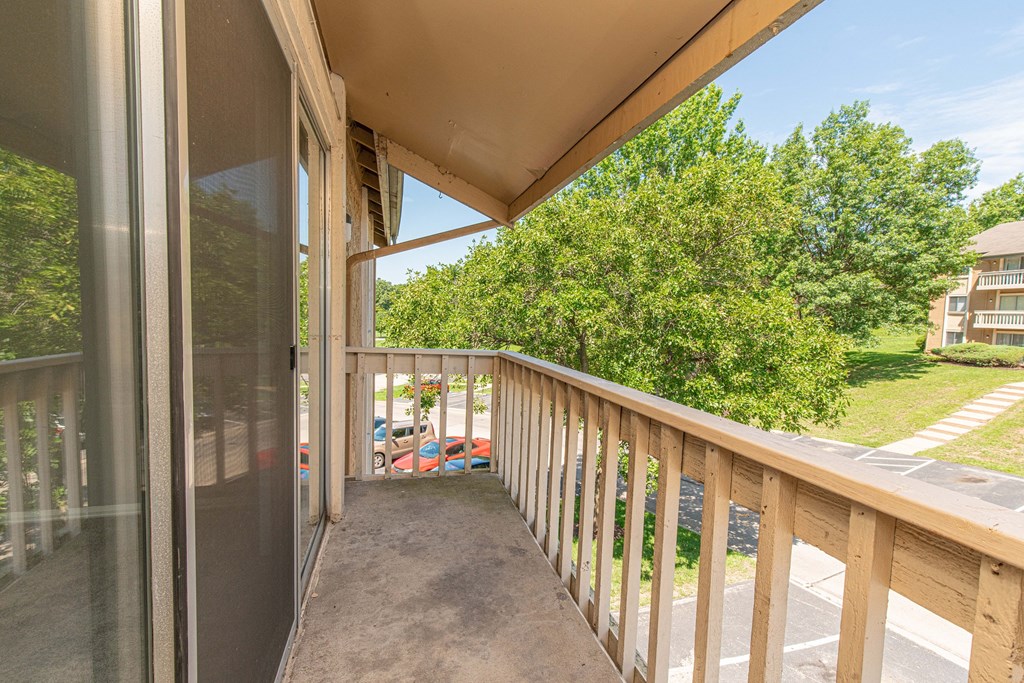 the balcony has a view of the yard and the trees