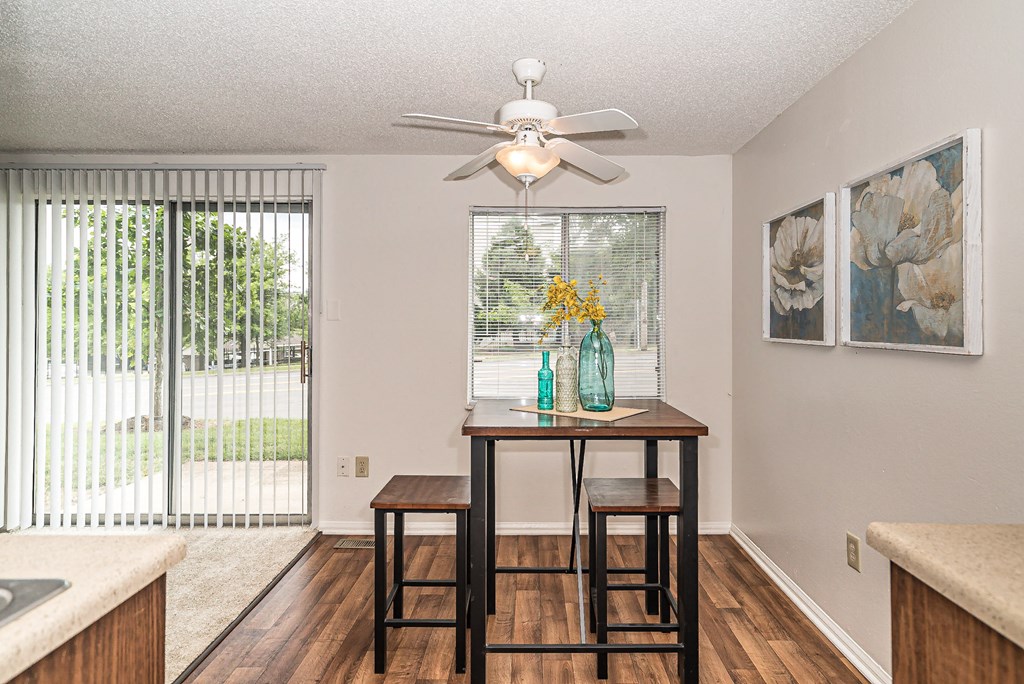 a kitchen with a table with two stools and a ceiling fan