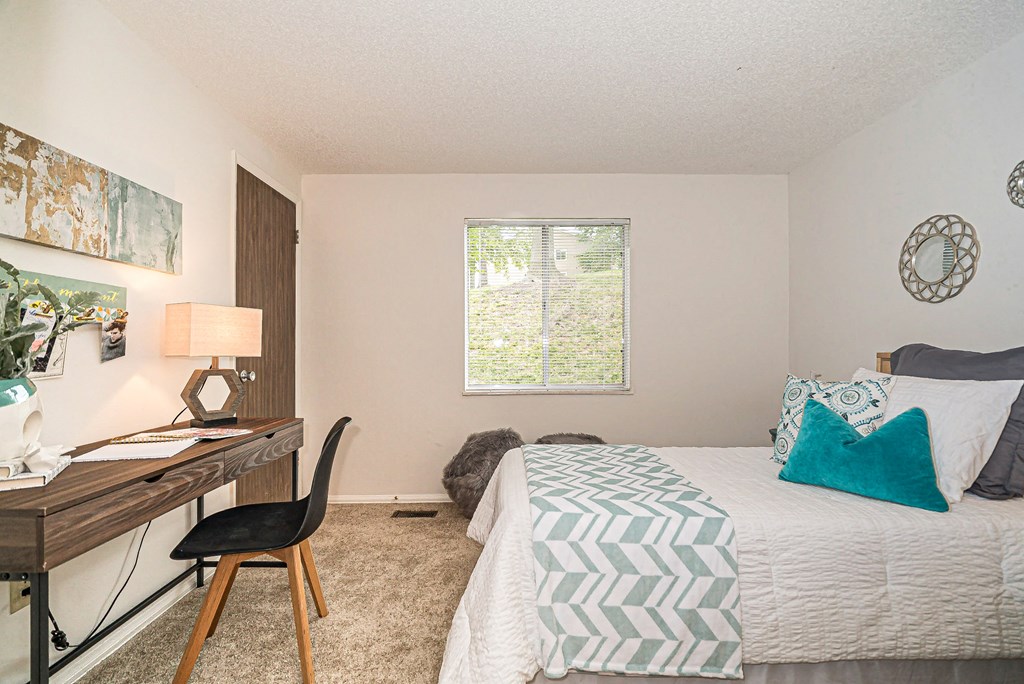 a bedroom with a bed and a desk and a window