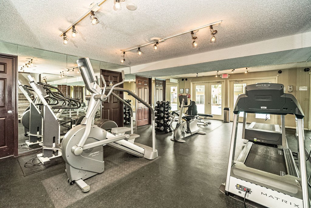 a gym with cardio equipment and weights on the floor