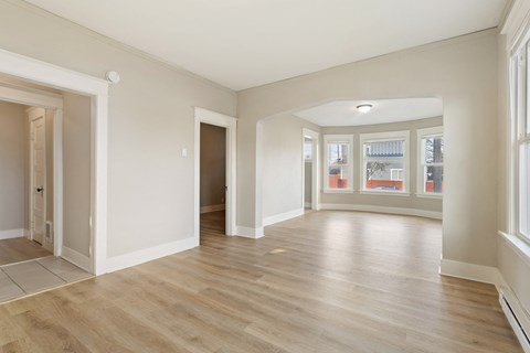 a living room and dining room with white walls and wood floors