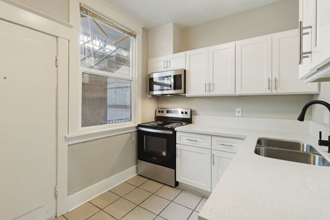 a kitchen with white cabinets and black appliances and a window