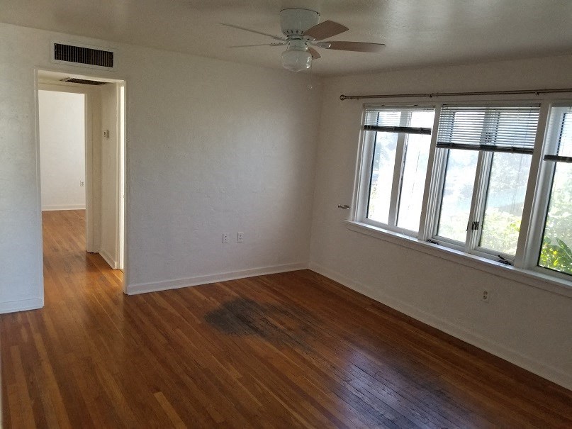 an empty living room with wood floors and a ceiling fan