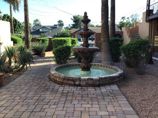a fountain in the middle of a brick sidewalk