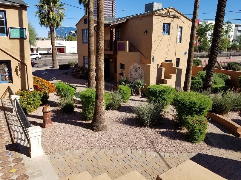 a courtyard with a building and trees and a bench