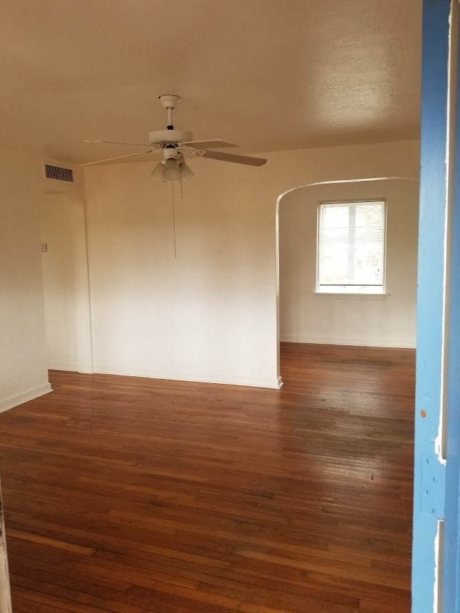 an empty room with wood floors and a ceiling fan