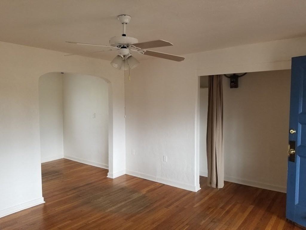 an empty room with a ceiling fan and wood floors