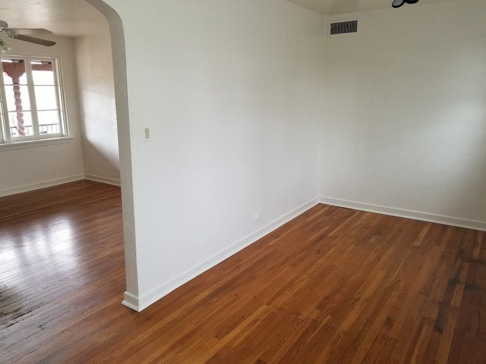 an empty living room with white walls and wood floors