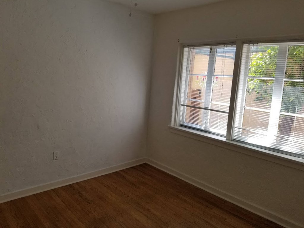 an empty room with a window and a wooden floor